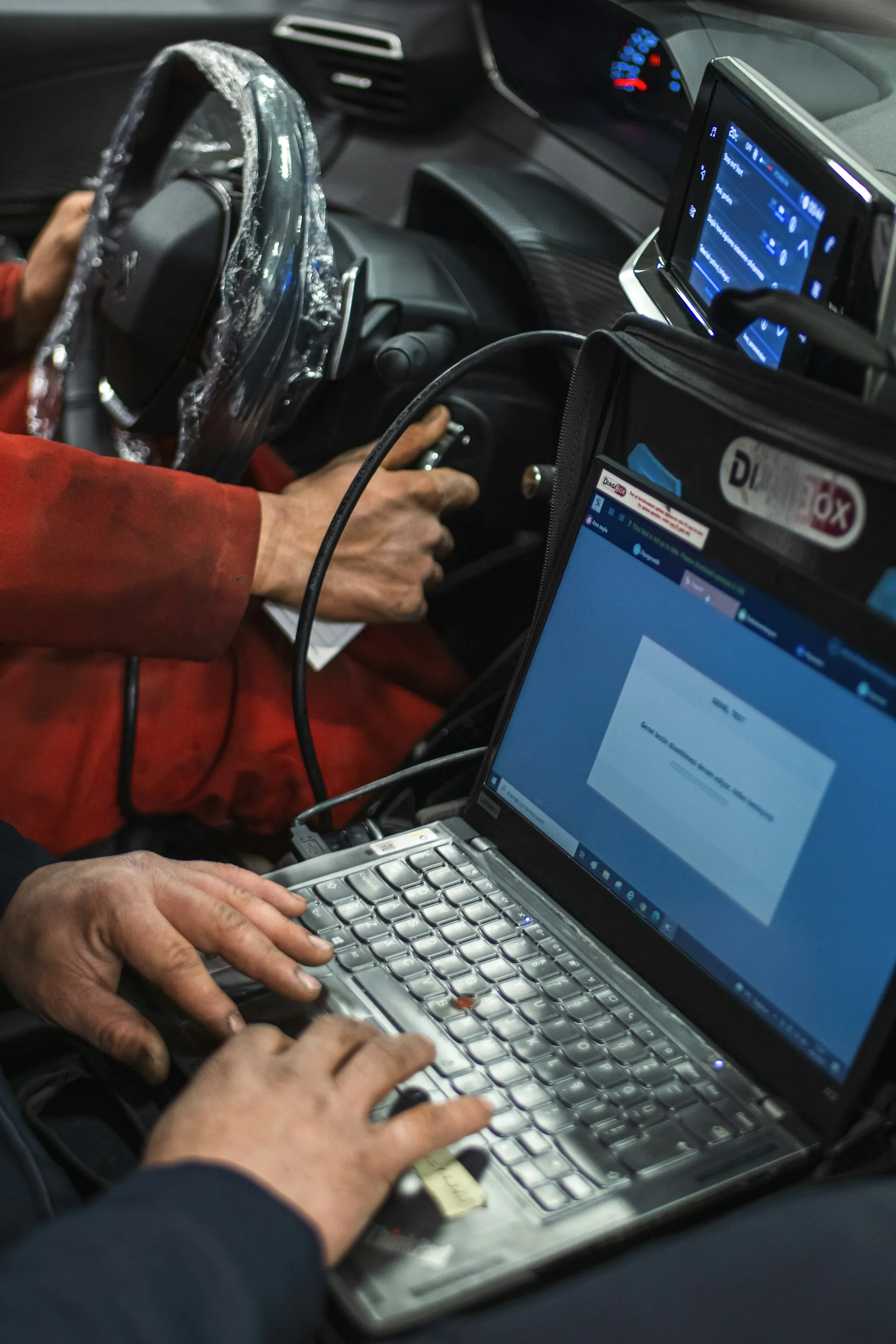 Technician connecting a laptop to diagnose a vehicle