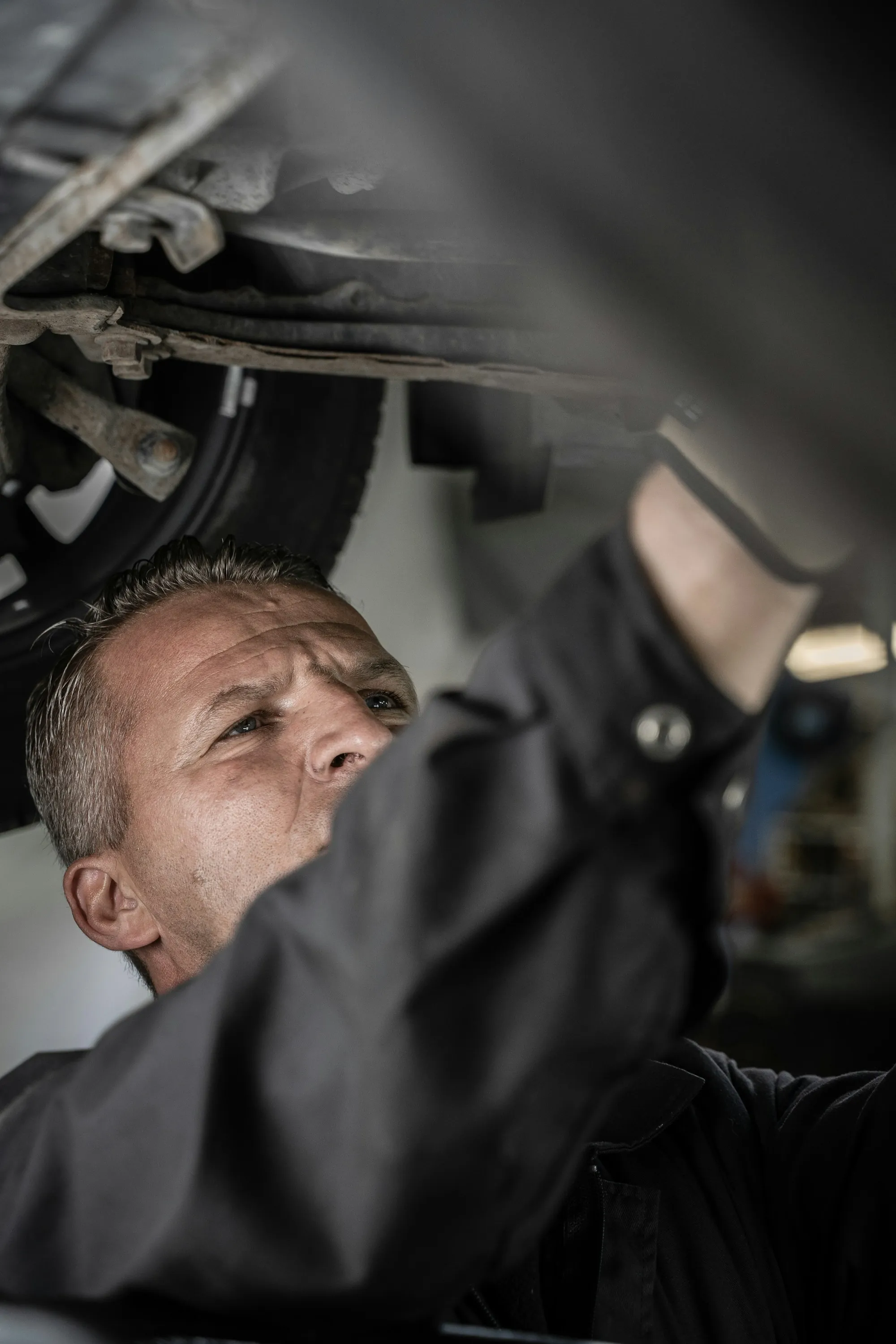 Mechanic examining the underside of a lifted vehicle