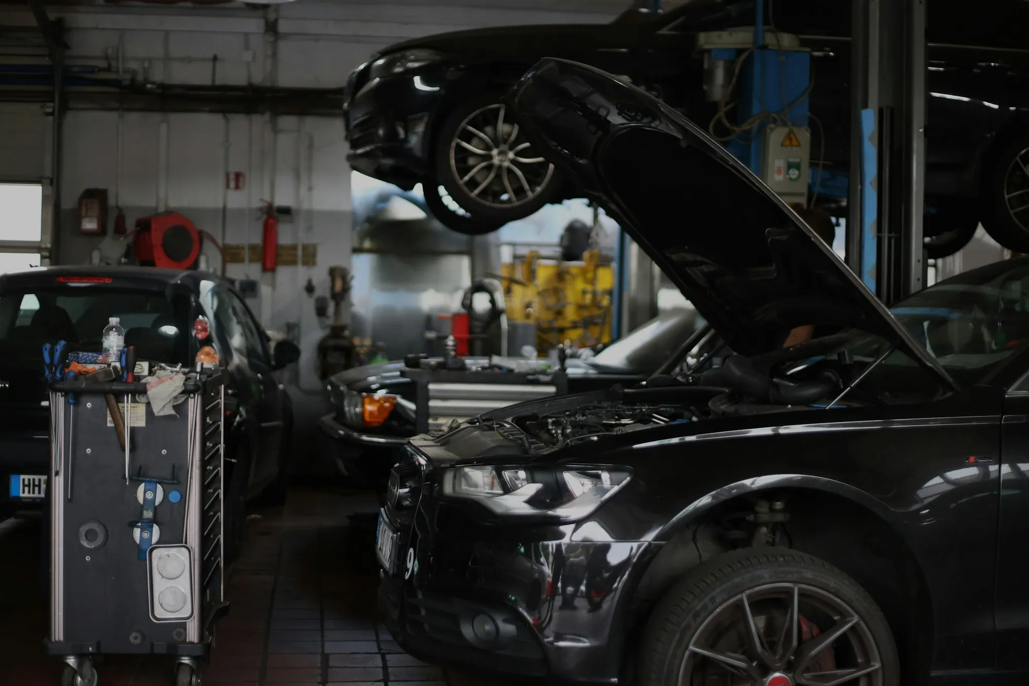 Dark workshop with an SUV raised and its hood open